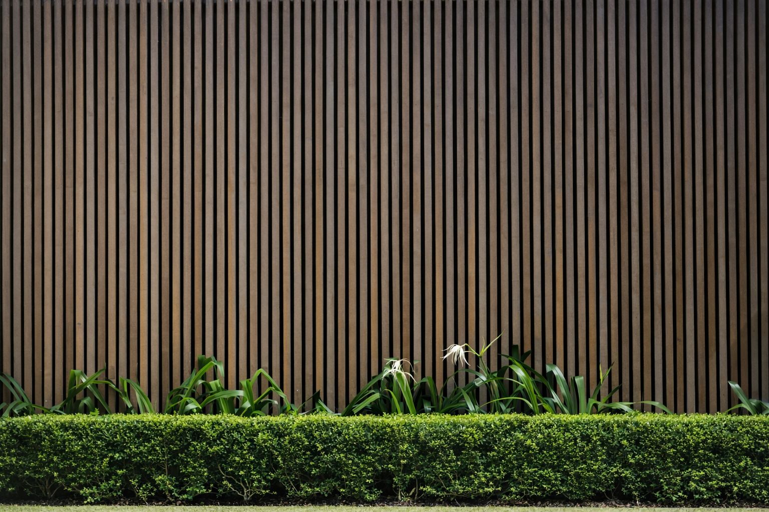 Panneau tasseau bois vertical sur un mur extérieur avec haie de jardin.