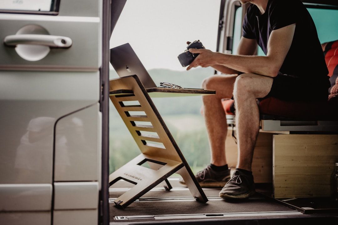Un homme travaillant sur un ordinateur portable dans un van aménagé.