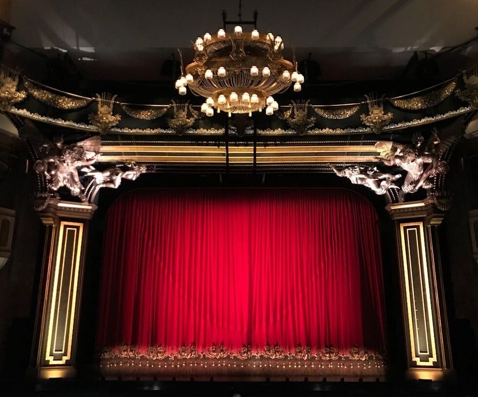 Scène de théâtre ornée, encadrée par un rideau rouge fermé
