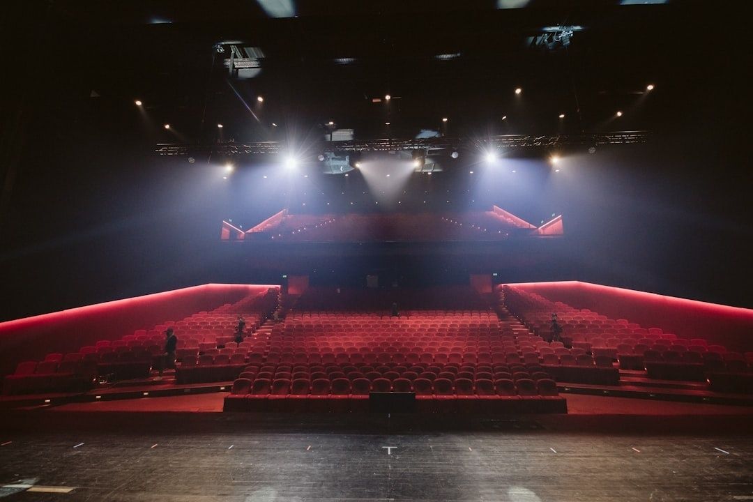 Salle de spectacle rouge éclairée, vue depuis la scène vers le public